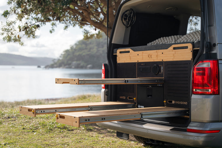 Wide shot of the Vagabond modular van conversion kit installed inside a VW Multivan, with the slide-out kitchen, storage drawer and seating all stowed.