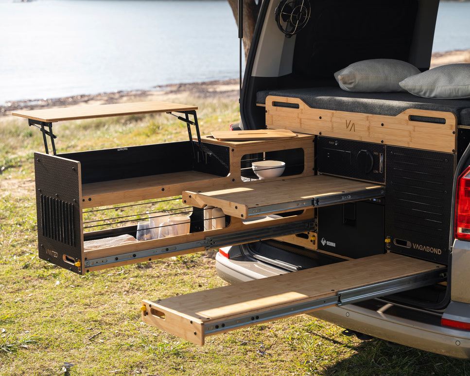 Vagabond pull-out outdoor seating extended beside the van with two people seated on each side at a table, seating four and rated to 180kg.