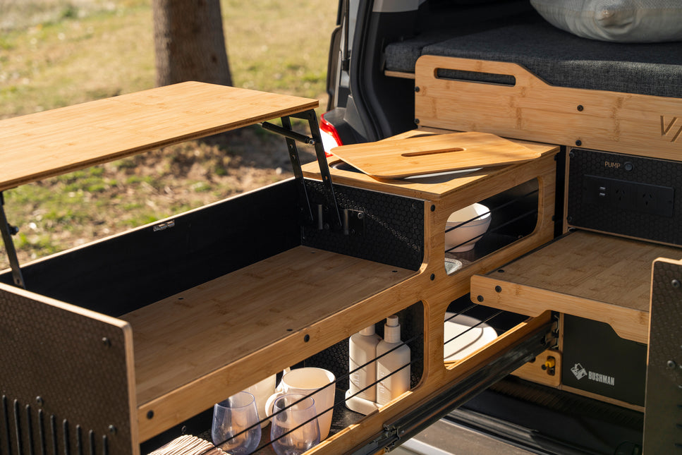  Vagabond modular van conversion kit with the full slide-out kitchen extended, showing a 30-litre chest fridge, cooktop and prep area in use.